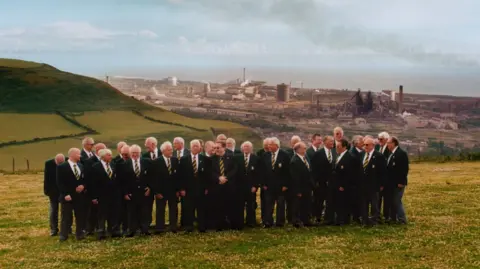 A male voice choir on green hills overlooking Port Talbot