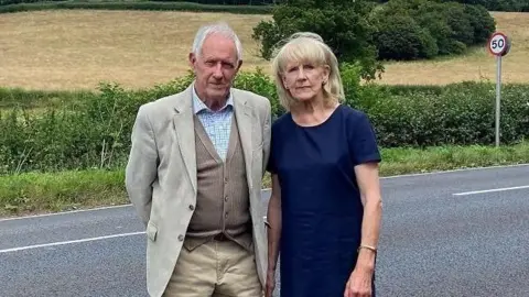 Peter Bate stands next Scilla Barney on the A39 road near Tivington