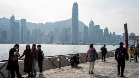 People walk on the waterfront in Hong Kong