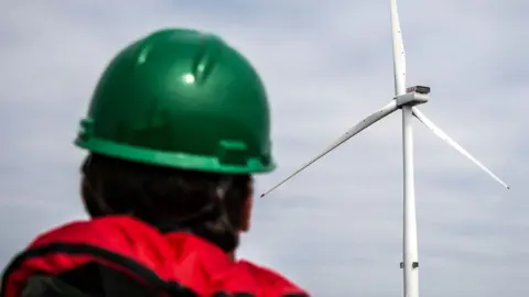 A man looking at a wind turbine under construction at the Seagreen Offshore Wind Farm, off the coast of Scotland