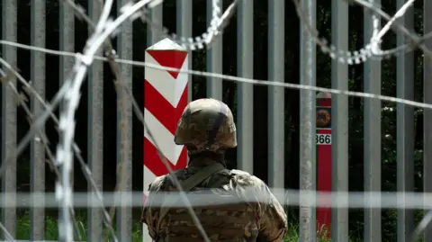 Reuters A soldier stands guard near the fence on the Belarusian-Polish border