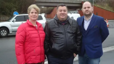 LDRS Councillors Steph Exell, Kevin Small and Jim Robbins. Steph has light hair which is tied back. She is wearing a red coat. Kevin Small has short dark hair and is wearing a black coat. Jim Robbins is bald with facial hair. He is wearing a blue blazer and jeans. The three of them are stood in a line side by side, looking at the camera and smiling. 
