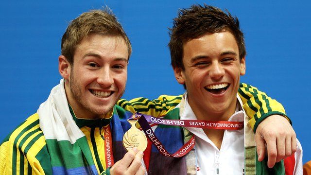Divers Matthew Mitcham (left) and Tom Daley (right) smiling as Mitcham holds up Daley's 2010 Commonwealth Games gold medal