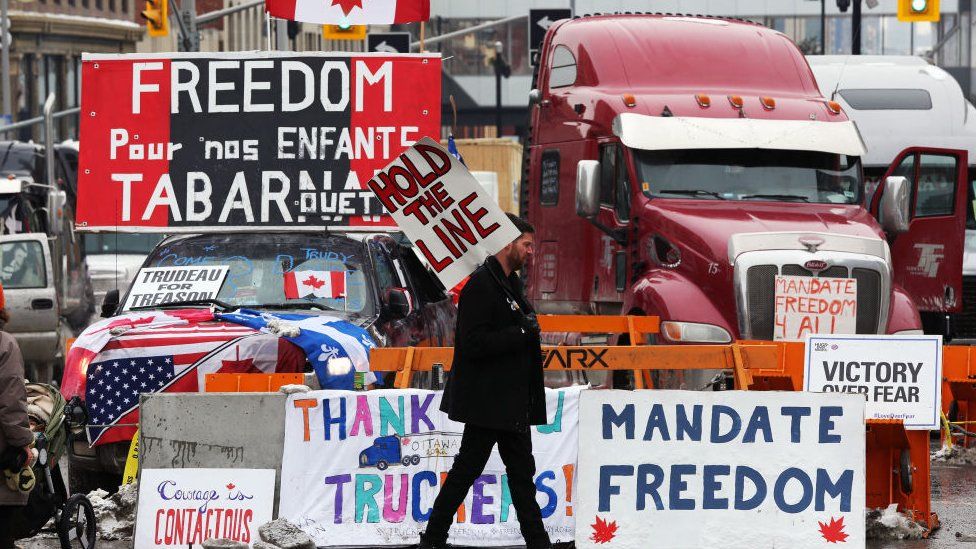 A protester walks in front of parked trucks as demonstrators continue to protest the vaccine mandates implemented by Prime Minister Justin Trudeau on 8 February 2022 in Ottawa