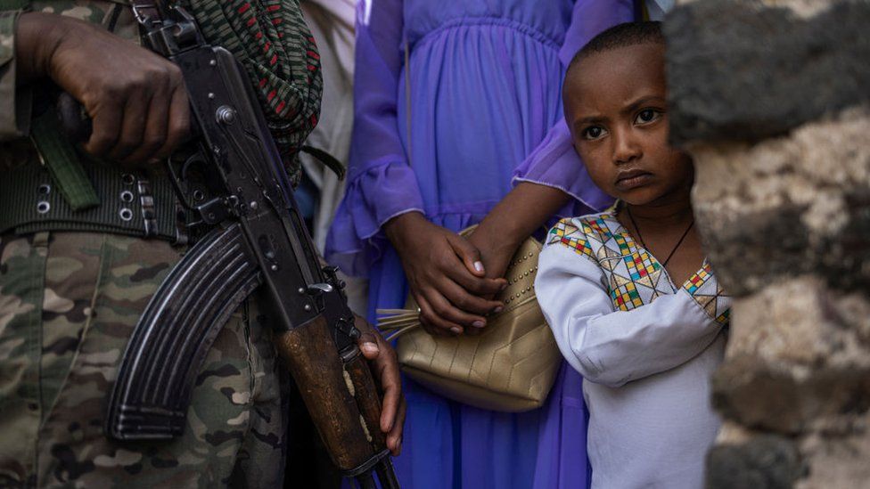 A member of the Amhara police force stands guard next to Ethiopian Orthodox worshippers.