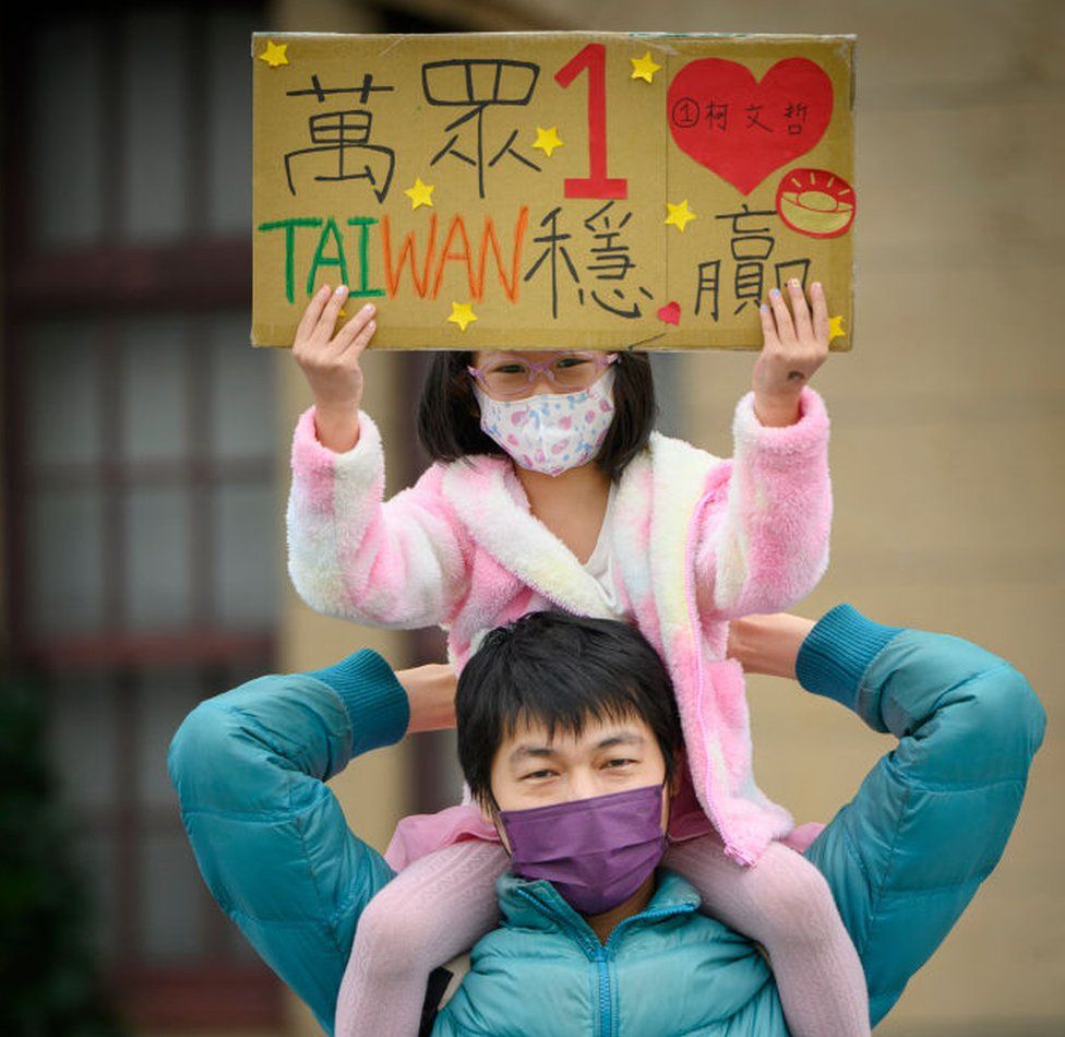 A woman holds up her daughter carrying a placard supporting the Taiwan People's Party