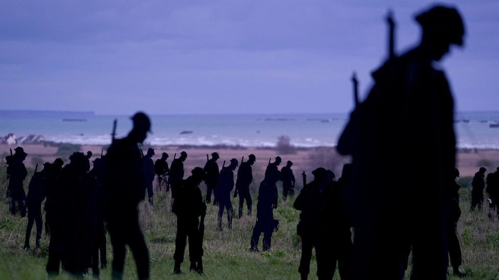 silhouettes of servicemen overlooking beach