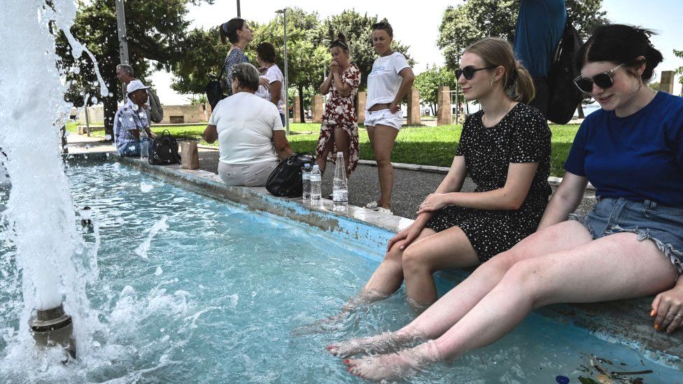 People cool off in a fountain in Thessaloniki, northern Greece