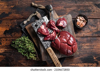 Raw lamb kidney, fresh offal meat on butcher board with herbs. Wooden background. Top view