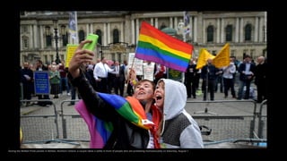 During the Belfast Pride parade in Belfast, Northern Ireland, a couple takes a selfie in front of people who are protesting homosexuality on Saturday, August 1.
 