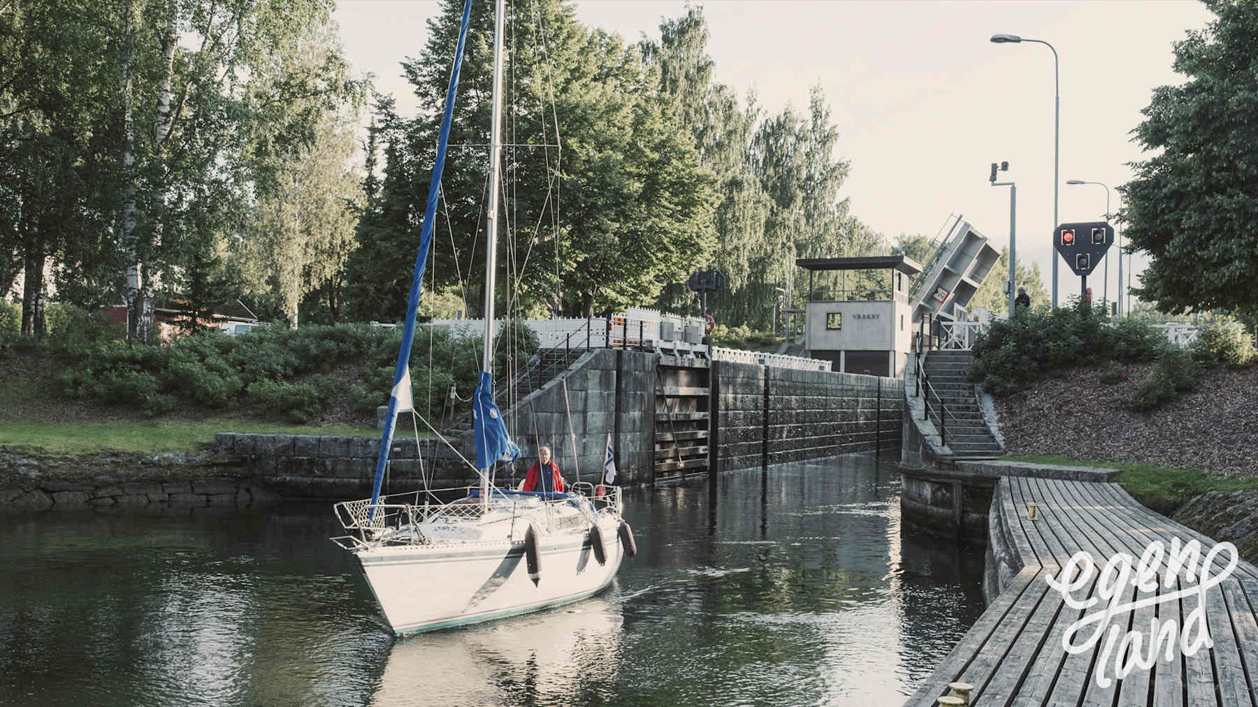 Segelbåt har precis kommit ut ur Vääksy kanal, kanalmynningen i bakgrunden.