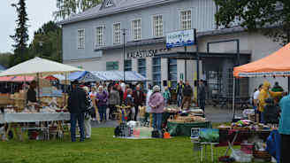 Torgförsäljning på gräsmatta framför hus med skylten "kalastusmuseo", fiskerimuseum.