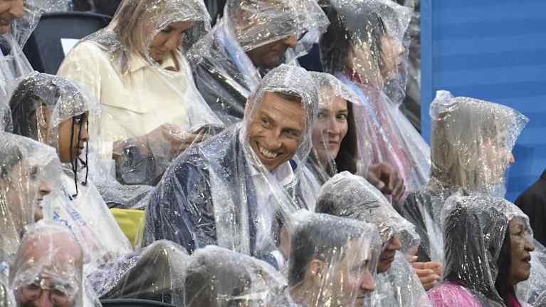 Finnish President Alexander Stubb in a poncho as rain falls.