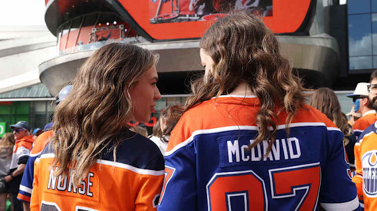 Kaksi NHL-joukkue Edmontonin naisfania seisoo selin jäähallin ulkopuolella.