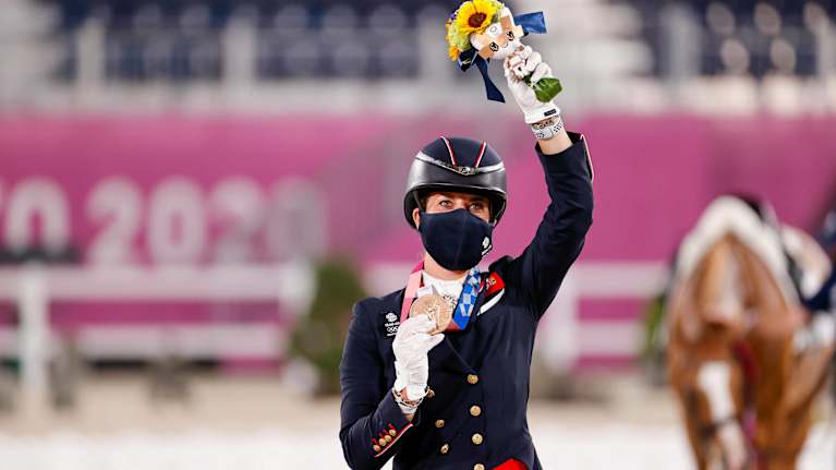 Charlotte Dujardin vilkuttaa kuvaajille mitali kaulassaan Tokion olympialaisissa.