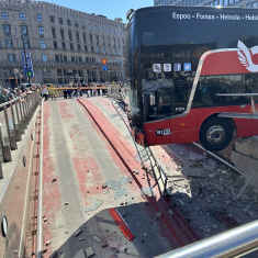 En röd buss hänger halvvägs över en bilramp.