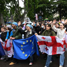 En grupp unga människor håller upp Georgiens och EU:s flaggor.