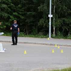Police investigators placing yellow cones on a road.