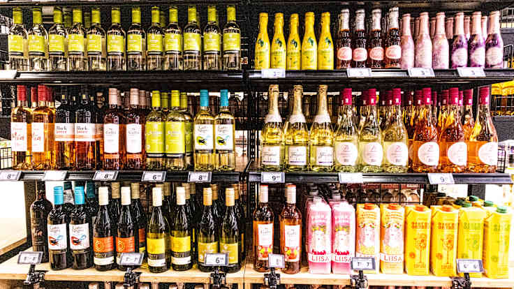 Photo shows a selection of wines on a shelf.