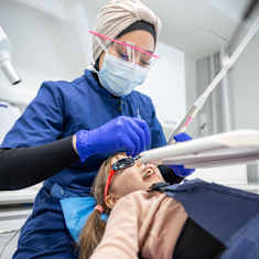 Dental nurse checks a child's teeth.