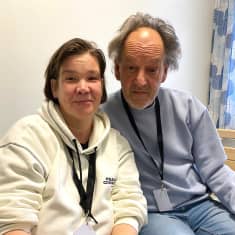 Lena Juvonen och Billy Lindqvist sitter på en säng