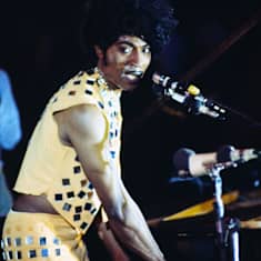 Little Richard seisoo lavalla, laulaa ja soittaa pianoa keltaisessa peilein koristellussa asussa.