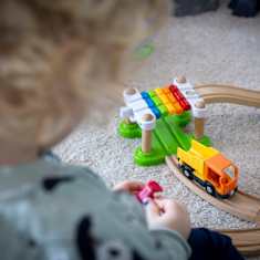 Lapsi leikkii lattialla junaradalla.