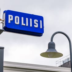 Poliisikyltti ja katulamppu taivasta vasten.