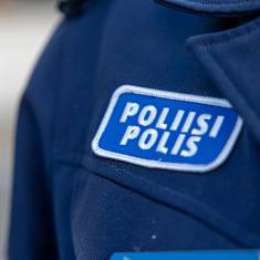 Siniseen vaatteeseen ommeltu hihamerkki, jossa lukee valkoisella poliisi ja polis.