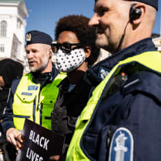 En demonstrant står mellan två poliser. 