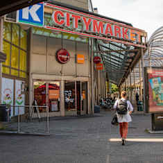 En person går förbi en byggnad med en stormarknad i.