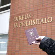 Passi kädessä Kajaanin oikeus- ja poliisitalon edustalla