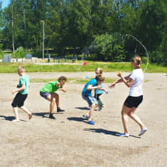 Barn på en sandplan kastar vattenballonger på varandra.