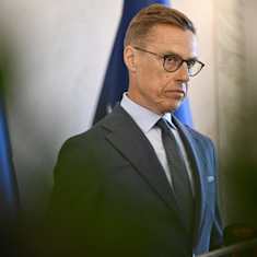 Stubb stands in front of the Finnish flag looking serious.