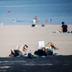 Människor njuter av solen på Sandudds badstrand i Helsingfors. 