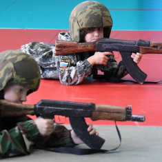 Unga barn som övar med träreplikor av automatvapnet Kalashnikov