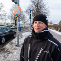 En man står invid en gata i centrala Borgå. Bakom honom syns bilar och en trafikkamera.