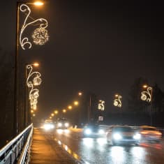 Bilar kör i mörkret, runtomkring finns julbelysning