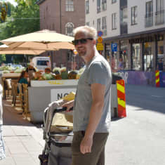 En kvinna och en man står på trottoaren på Kristinegatan. Mellan sig har de en barnvagn. 