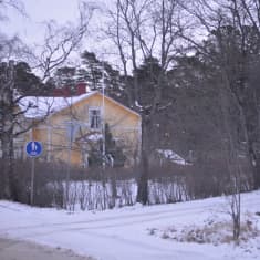 Vägkorsning på vintern, i bakgrunden ett gult trähus.