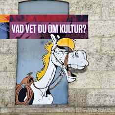 En stenhusfasad med två fönster och en mural som föreställer Lucky Luke och hans häst Jolly Jumper.