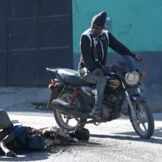 En passerande motorcyklist stannade för att titta på dödsoffer utanför fängelset i Port-au-Prince på söndagen. 