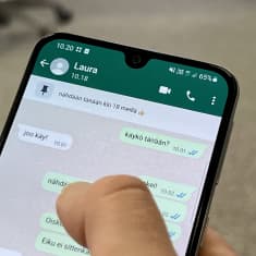 En telefonskärm med en Whatsappkonversation. På skärmen är en tumme. Samtalet är på finska och där kommer man överens om att ses samma kväll klockan 18.