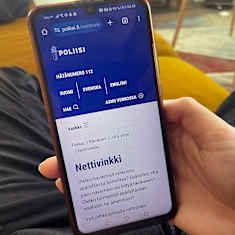 Nuoren kädessä matkapuhelin, jonka näytöllä näkyy poliisin nettivinkkisivu.