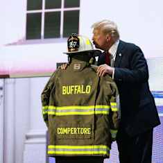 Donald Trump antaa suukkoa kypärälle, joka on nostettu palopelastajan takin päälle.