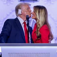 Donald Trump ja Melania Trump suukottavat toisiaan puhujanpöntössä.