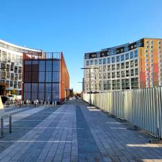 Flervåningshus intill ett torg med stenbeläggning.