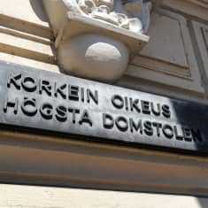 En svart skylt där det står "Högsta domstolen" på en ljusgul byggnad.