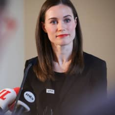 Sanna Marin fotograferad under presskonferens, i förgrunden mikrofoner.
