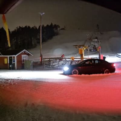 En personbil har fastnat i snön vid foten av en slalombacke.